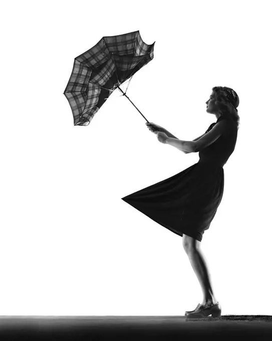 1930s 1940s ANONYMOUS SILHOUETTE OF TEENAGE  GIRL WITH UMBRELLA TURNED INSIDE OUT IN THE WIND