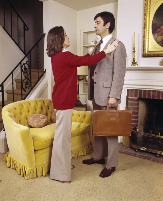 1970S Wife Adjusting Jacket Of Executive Husband Ready To Leave For Work Couple Man Woman