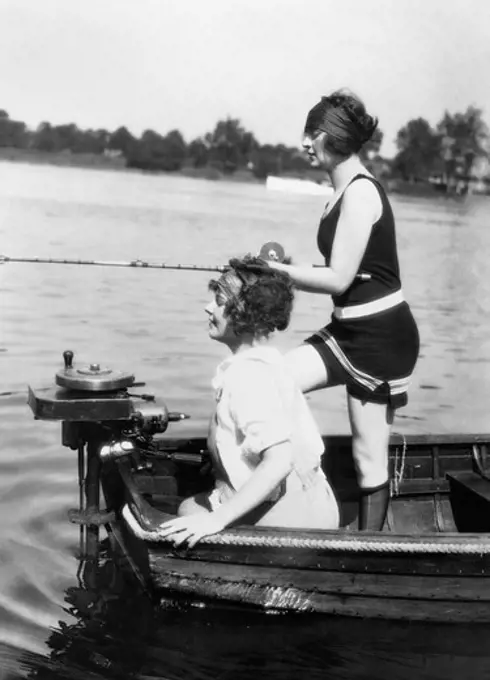 1920S 1930S Two Women Fishing From Stern Of Small Boat With Motor Outdoor One Woman Wi Wearing Bathing Suit