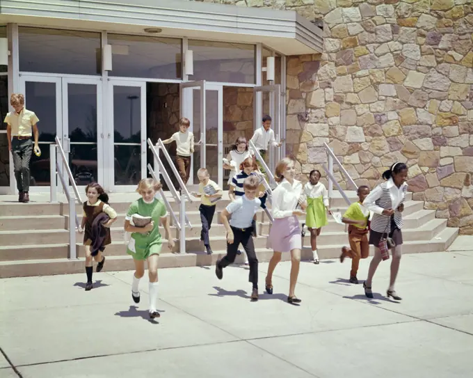 1960s 1970s GROUP OF ETHNICALLY DIVERSE KIDS RUNNING OUT OF SCHOOL BUILDING AT END OF DAY OR END OF SCHOOL YEAR SUMMER BREAK