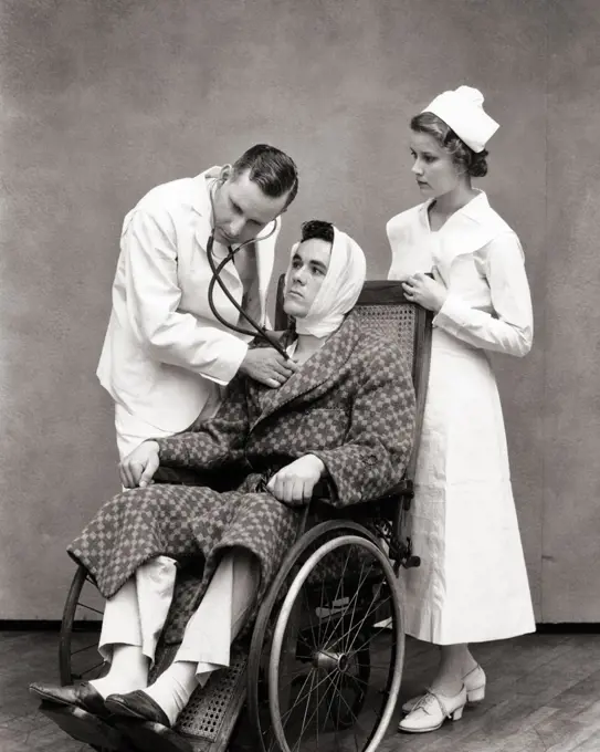 1930s NURSE STANDING BEHIND WHEELCHAIR PATIENT WEARING ROBE AND BANDAGED HEAD AS DOCTOR LISTEN TO HIS HEART WITH STETHOSCOPE 