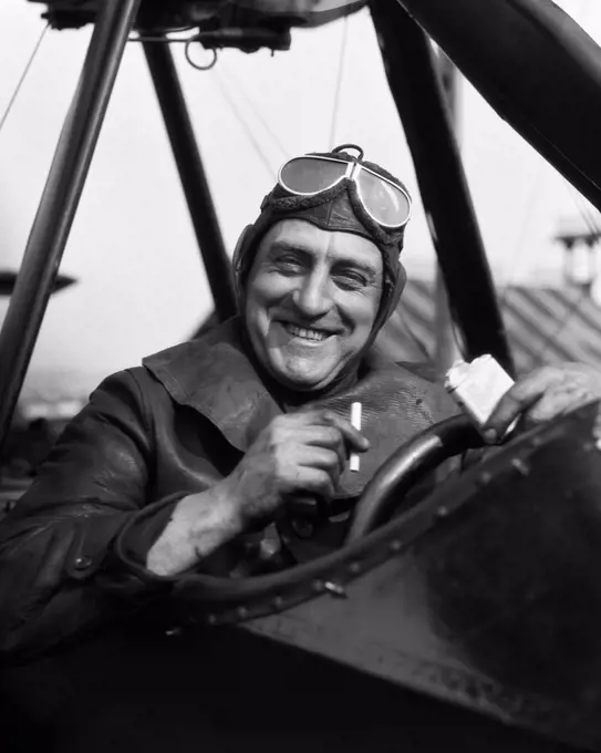 1920S 1930S Pilot Smiling Man In Cockpit Of Airplane Taking Cigarette Out Of Pack