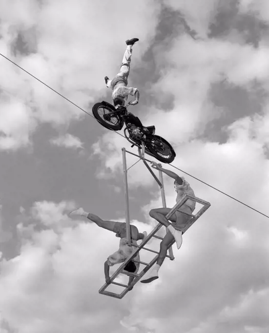 1960S High-Wire Act With Man Standing On His Head On Motorcycle & 2 Men On Ladder Below Him