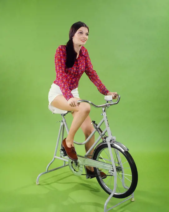 1970s BRUNETTE WOMAN EXERCISING ON STATIONARY BICYCLE