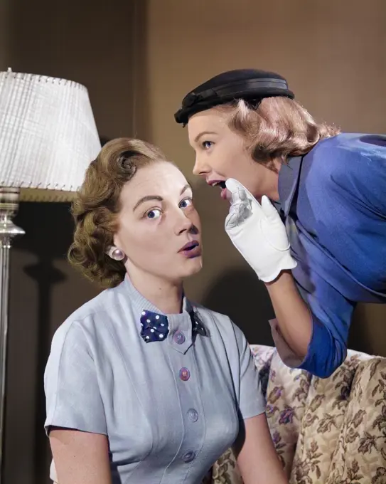1950s WOMAN IN HAT & WHITE GLOVES LEANING DOWN TO WHISPER GOSSIP TO FRIEND