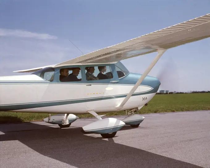 1960s FOUR BUSINESSMEN MEN EXECUTIVES SITTING IN CESSNA SKYLANE PRIVATE PROPELLOR AIRPLANE TAXING ON TARMAC RUNWAY