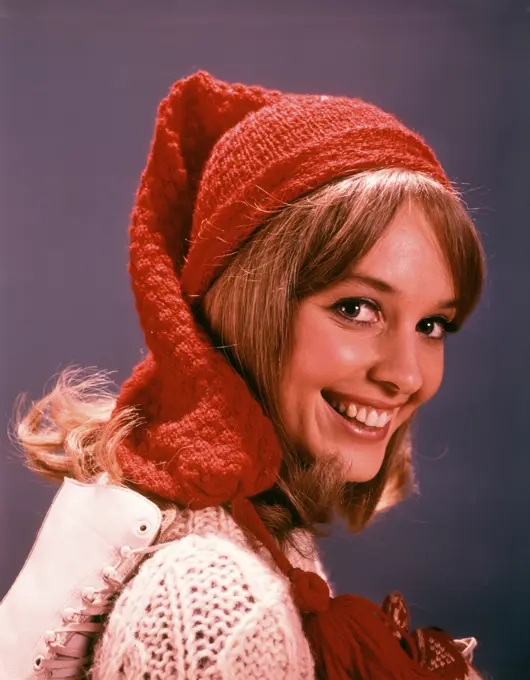 1960s SMILING YOUNG WOMAN WITH ICE SKATES WOOL HAT AND SWEATER LOOKING AT CAMERA 