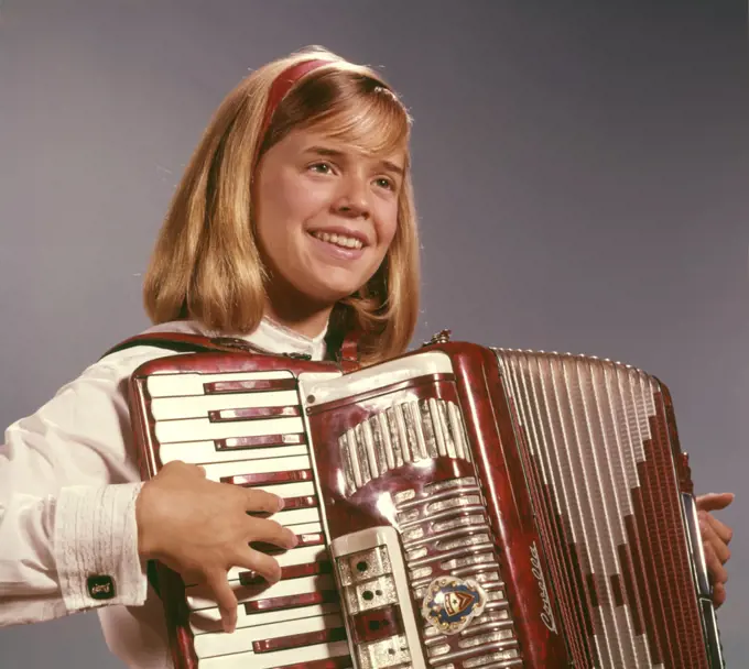 1960s 1970s SMILING BLOND TEENAGE GIRL MUSICIAN PERFORMER PLAYING ACCORDION MUSICAL INSTRUMENT