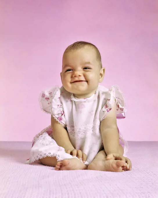 1970s BABY GIRL IN PINK SITTING SMILING