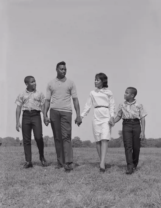 1960S African-American Family Holding Hands Walking In Grassy Field