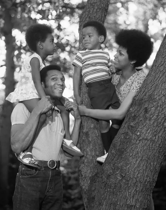 1970S African American Family Outdoors By Trunk Of Tree Mother Father Boy Girl