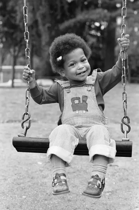 1970S 1980S African American Girl In Overalls Sitting On Playground Swing