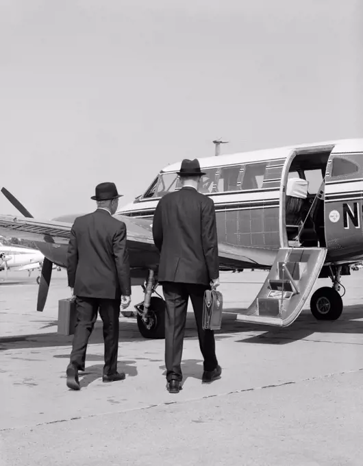 1960S Two Businessmen Walking Together To A Small Private Propeller Airplane Carrying Briefcase