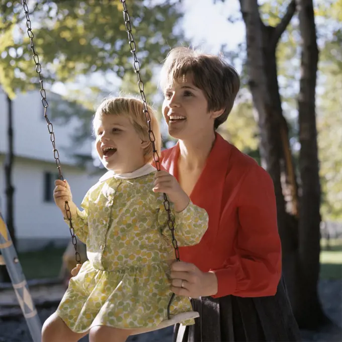 1960S 1970S Smiling Mother Pushing Laughing Girl Daughter On Backyard Swing