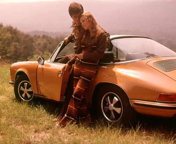 1970S Stylishly Dressed Couple Standing Together Leaning On A Convertible Porsche Automobile Sports Car