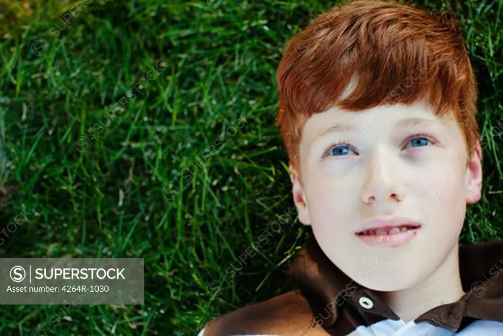 Boy lying on grass looking up