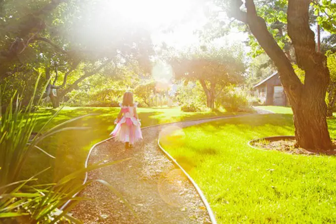 Girl in princess outfit walking on path in sunlight