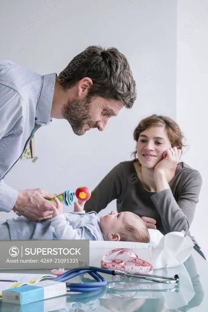 Doctor examining a 3 month old baby girl with her mother.