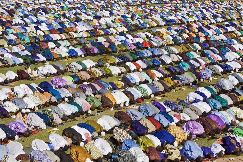 Mali, Mopti. A huge gathering of brilliantly dressed Muslim men pray to Allah at an open-air service to commemorate the end of the Muslim holy month of Ramadan.  This celebration is known as Idd el Fitr.