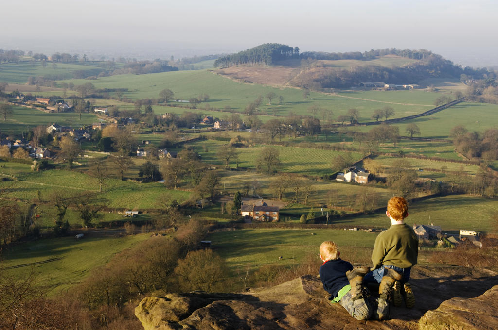 England, Cheshire, Bickerton Hils. Two young visitors enjoy the views out across the Cheshire Plains from the cliffs of Bickerton Hills. (MR).