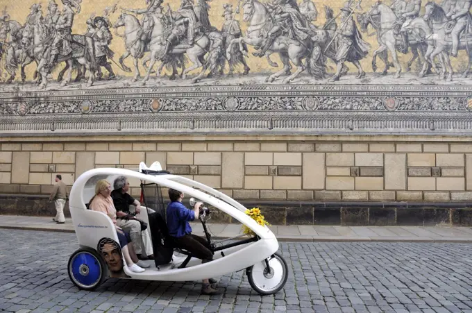 Tricycle cab wandering along the Furstenzug (Procession of the Princes) mural. Dresden, Germany
