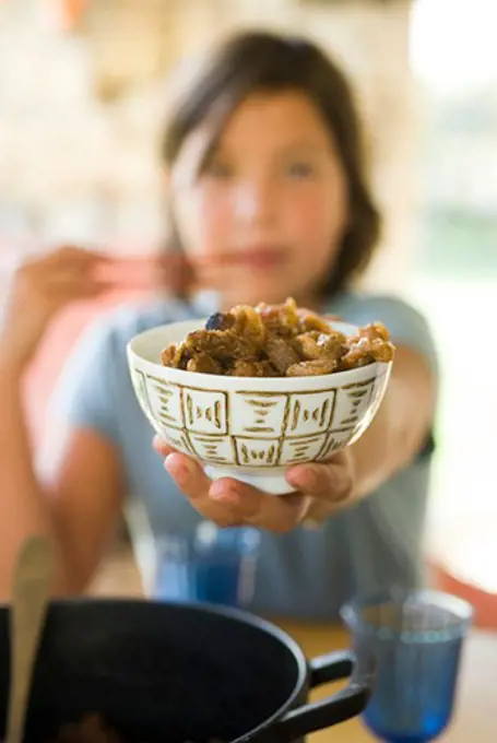 Girl holding out bowl of cooked food