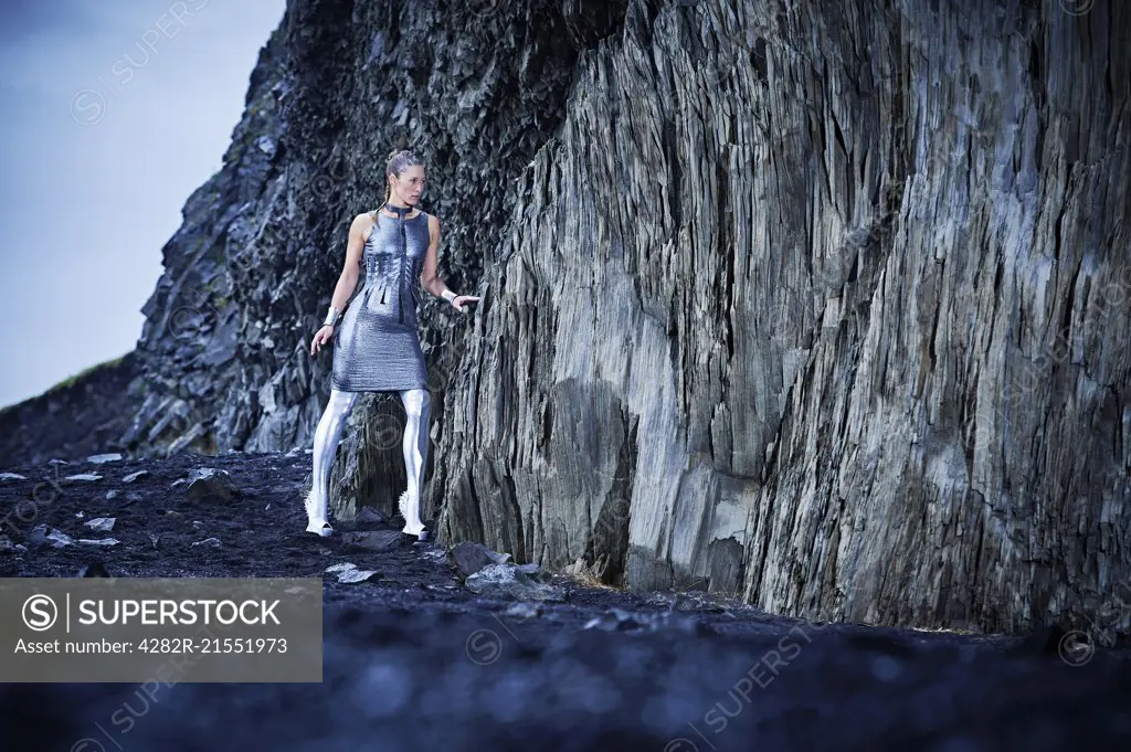 Young women in silver outfit walking with caution into a cave in southern Iceland.