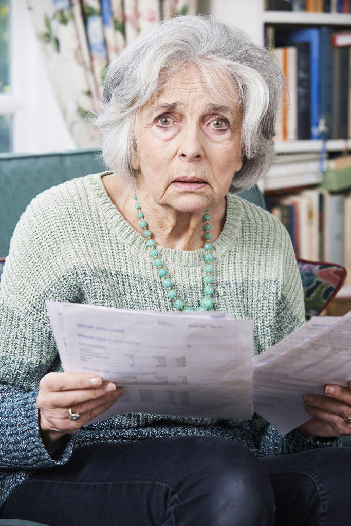 Senior Woman Going Through Bills And Looking Worried