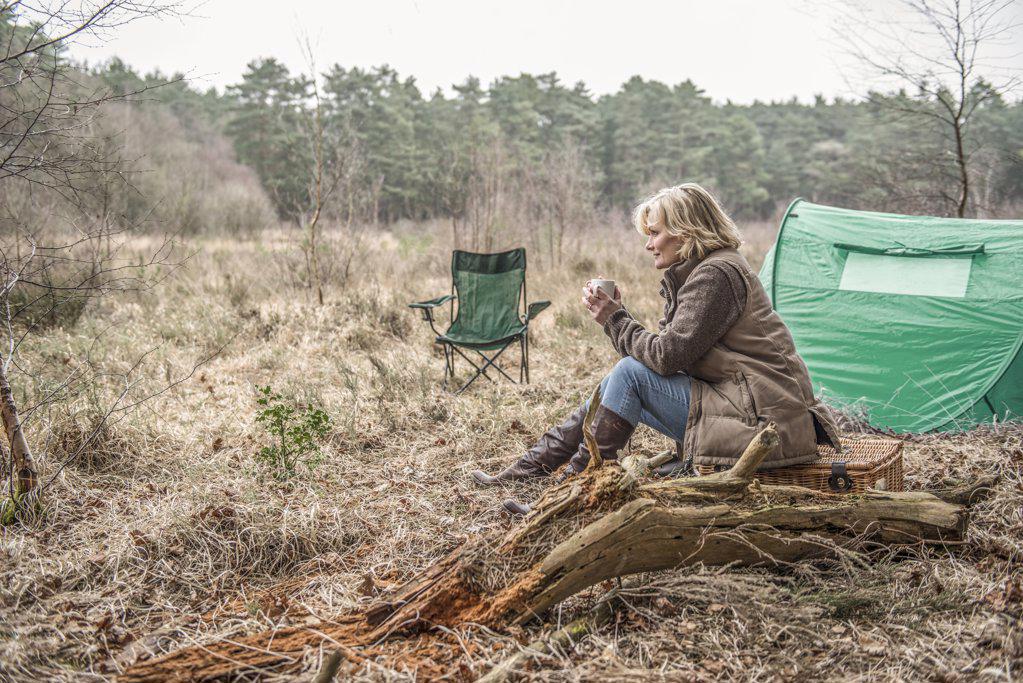 Senior lady sitting enjoying the wilderness from her campsite.