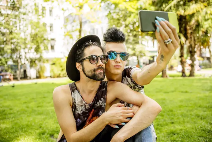 A gay couple taking selfies in a park in London.