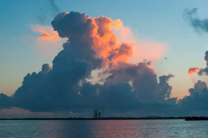 USA, Florida, Cape Canaveral, Distant view of rain clouds over space rocket launching station, Rain showers glow orange in the sunrise over a Delta IV (Delta 4) rocket at Cape Canaveral, ready to launch a Global Positioning System (GPS) satellite on October 4, 2012.