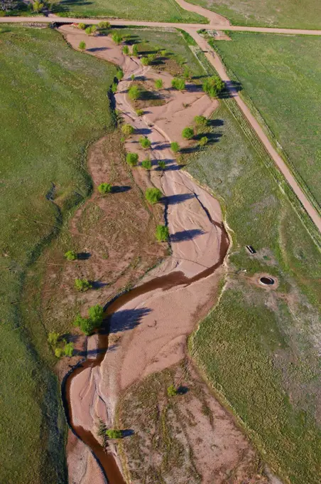 An aerial view of a creek striking through the plains of eastern Colorado. The creek meanders through a much broader bed, indicative of greater water levels.