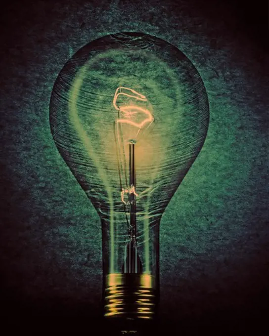 Photo Illustration of Light Bulb with Glowing Filament in Dramatic Light and Texture