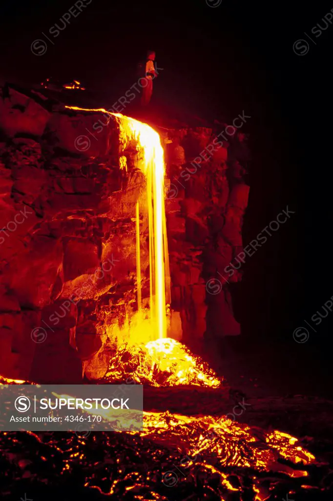 Man Standing by Lava Flowing Over a Cliff