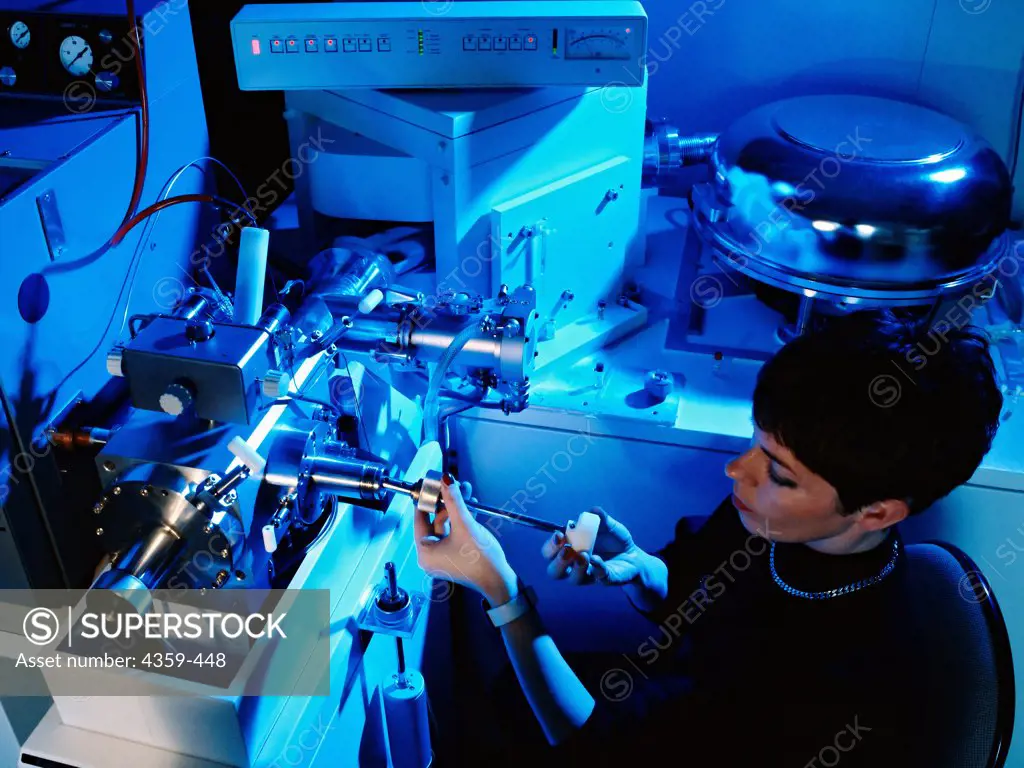 A laboratory assistant inserts a sample in a mass spectrometer for a mass  spectrometry reading. - SuperStock
