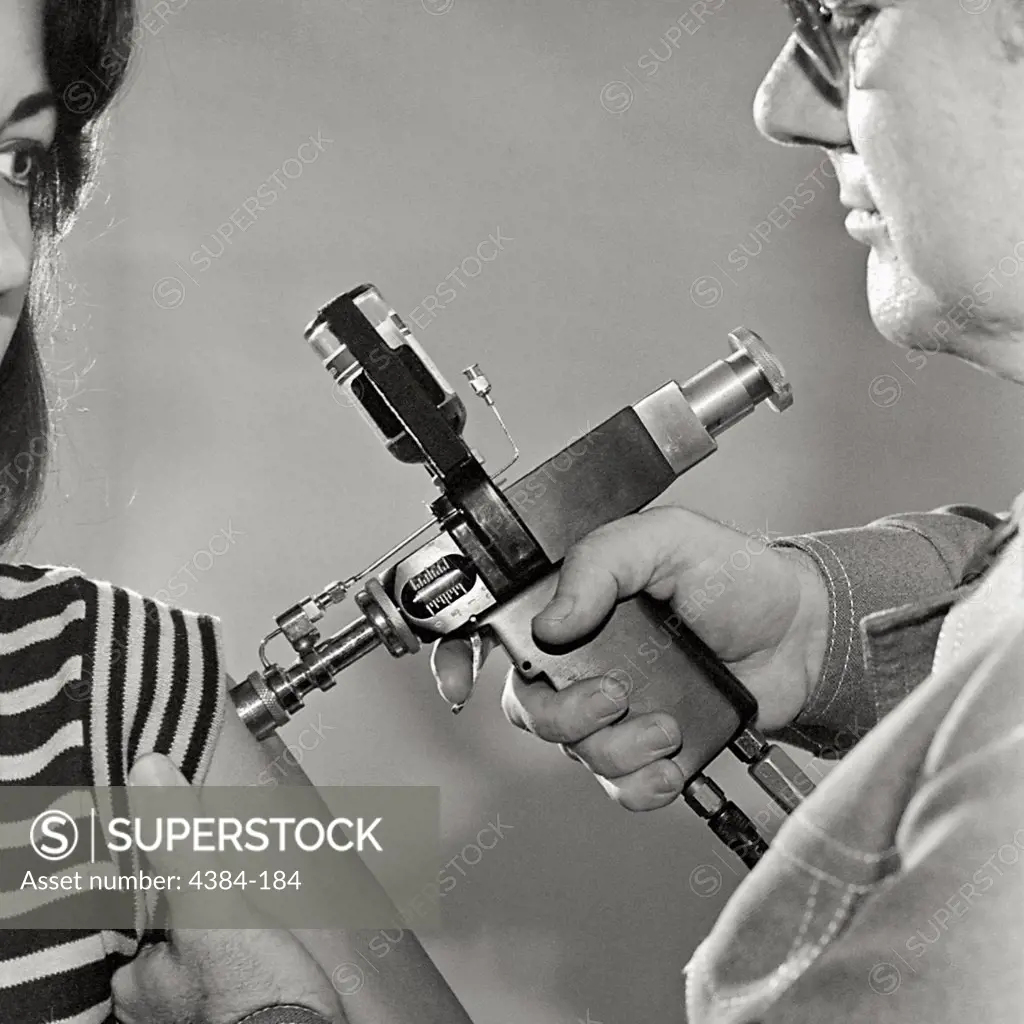 A man uses a jet injector to innoculate a woman during an immunization project for A/New Jersey/76 influenza.