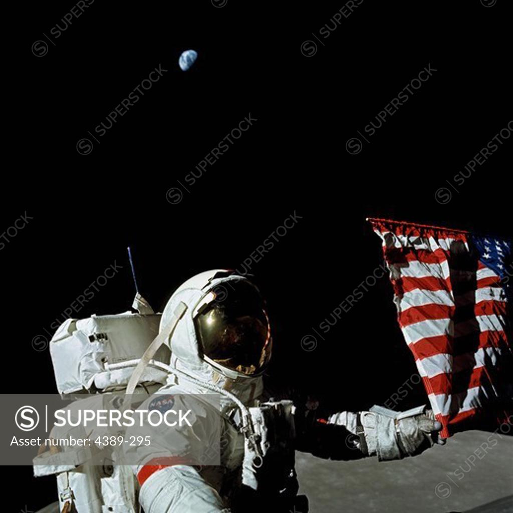 Stock Photo: 4389-295 An Apollo 17 Astronaut Stands Near an American Flag as the Earth Hangs Overhead