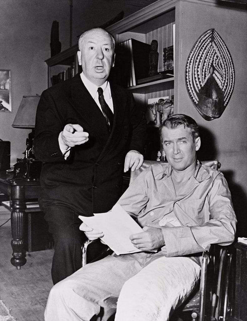 JAMES STEWART and ALFRED HITCHCOCK in REAR WINDOW (1954), directed by ALFRED HITCHCOCK.