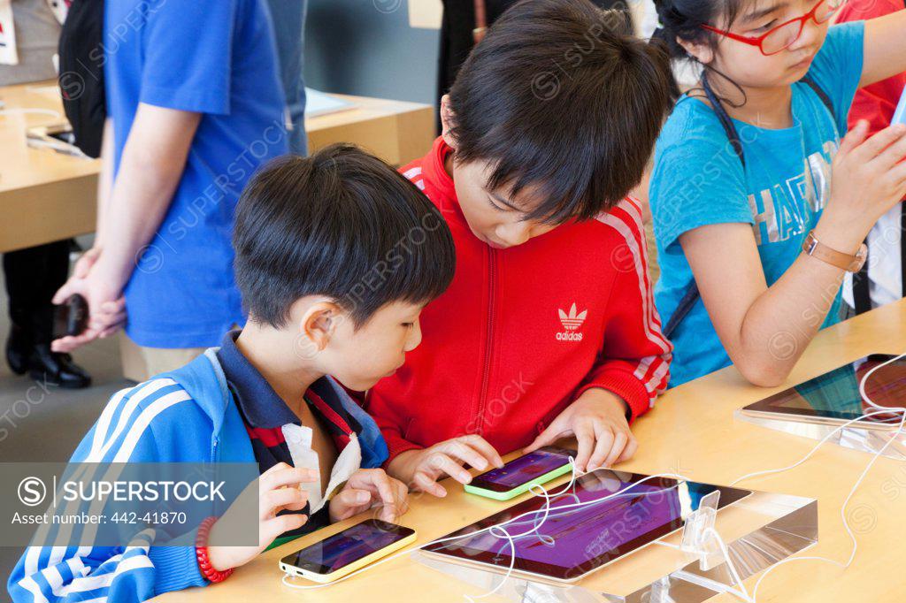 Stock Photo: 442-41870 China, Hong Kong, Apple Store, Children Looking at smartphone