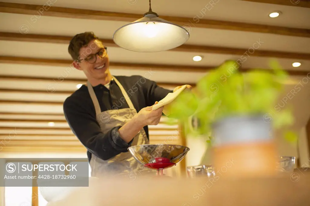 Happy young man making homemade dough in kitchen