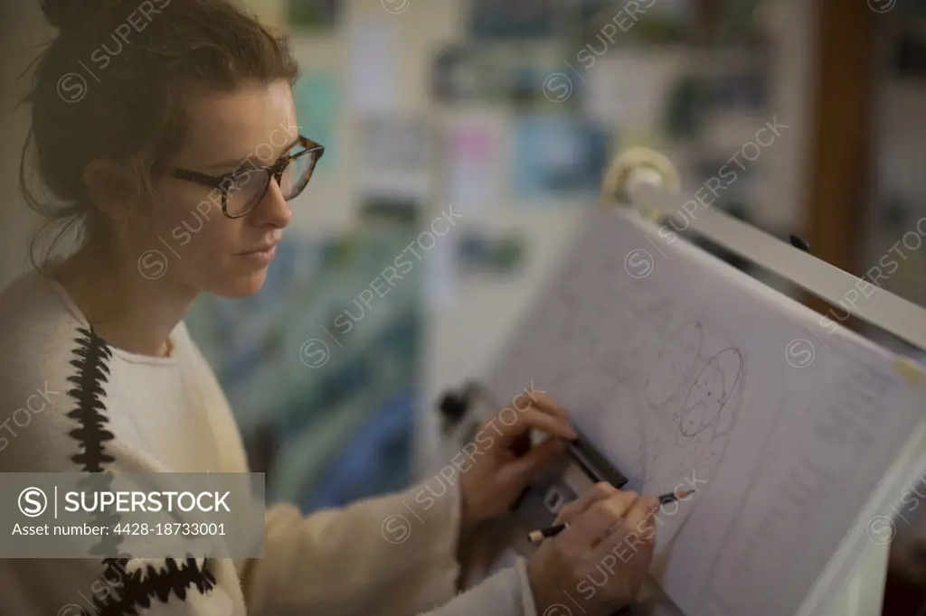 Focused female architect working at drafting table