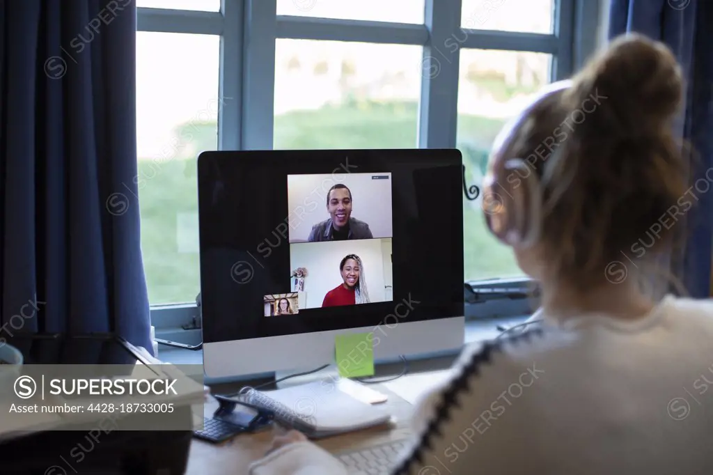Woman video conferencing with colleagues at computer in home office