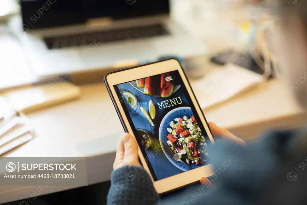 Woman looking at takeout menu on digital tablet