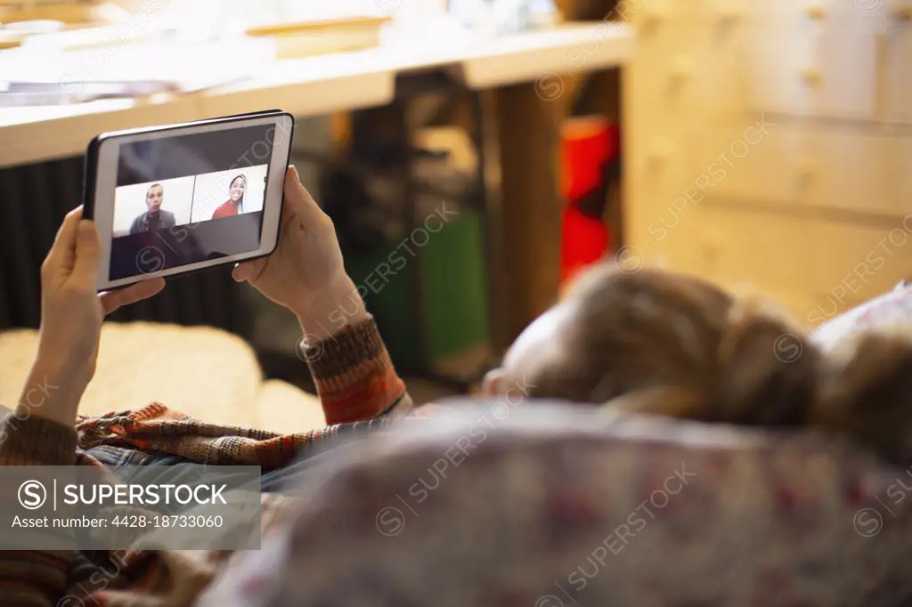 Woman video chatting with colleagues on digital tablet screen