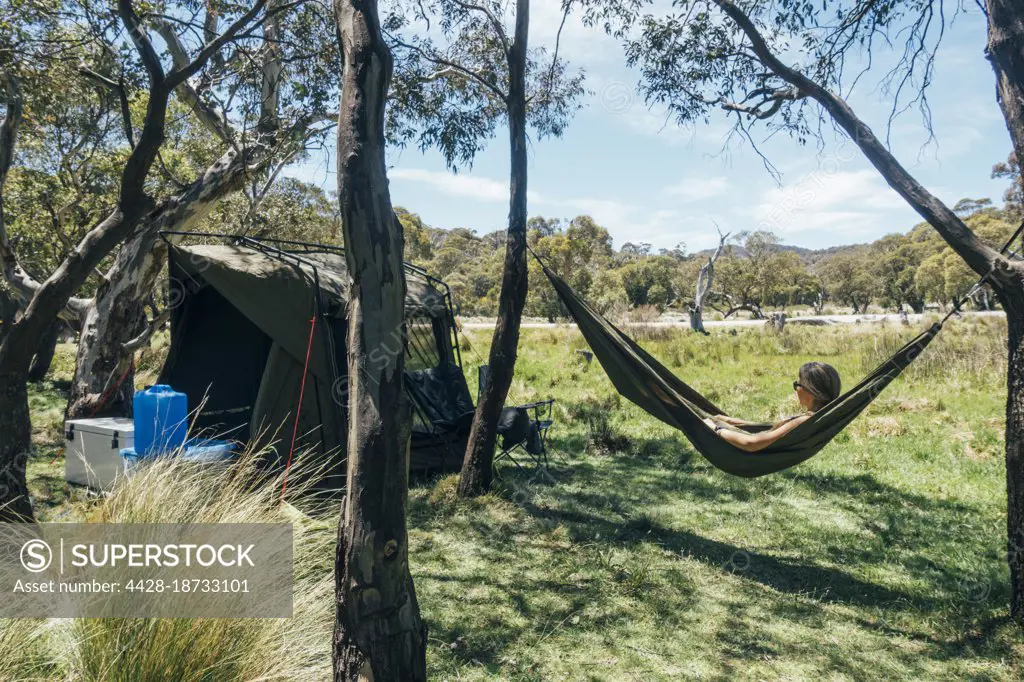 Woman relaxing in campsite hammock in sunny Australian bush