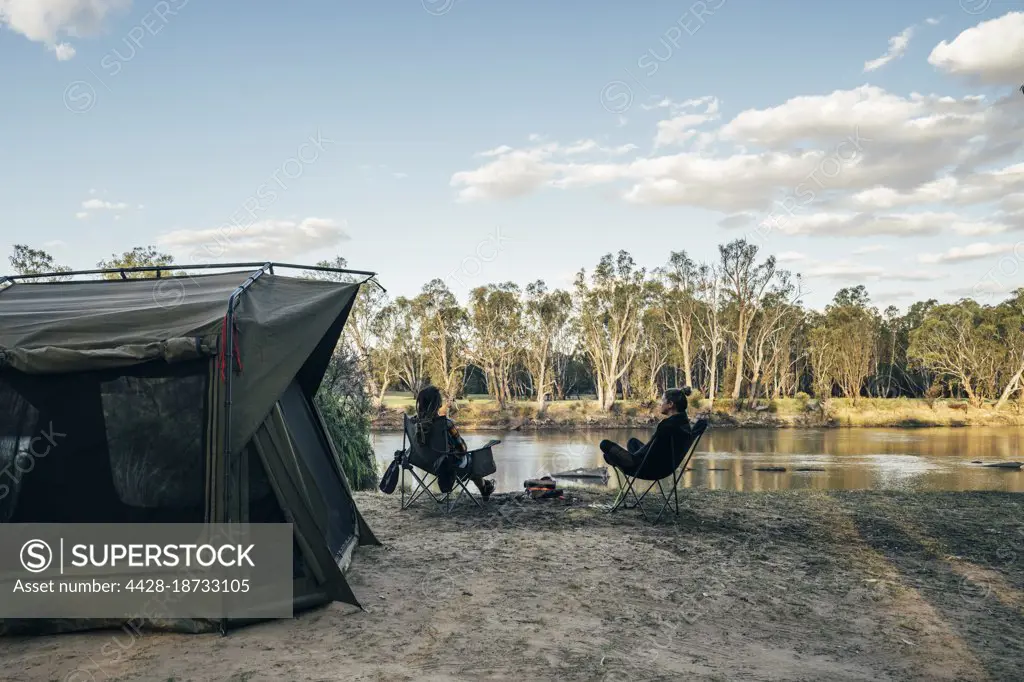 Couple relaxing outside tent at lake in remote Australian bush
