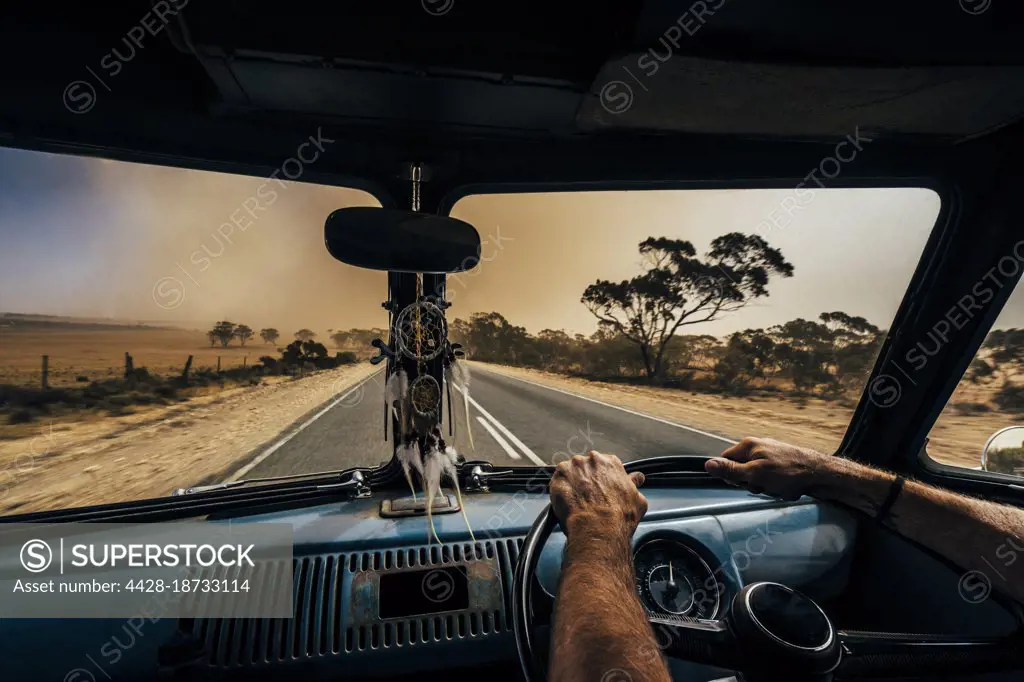 Man driving van on remote desert road, Australian bush
