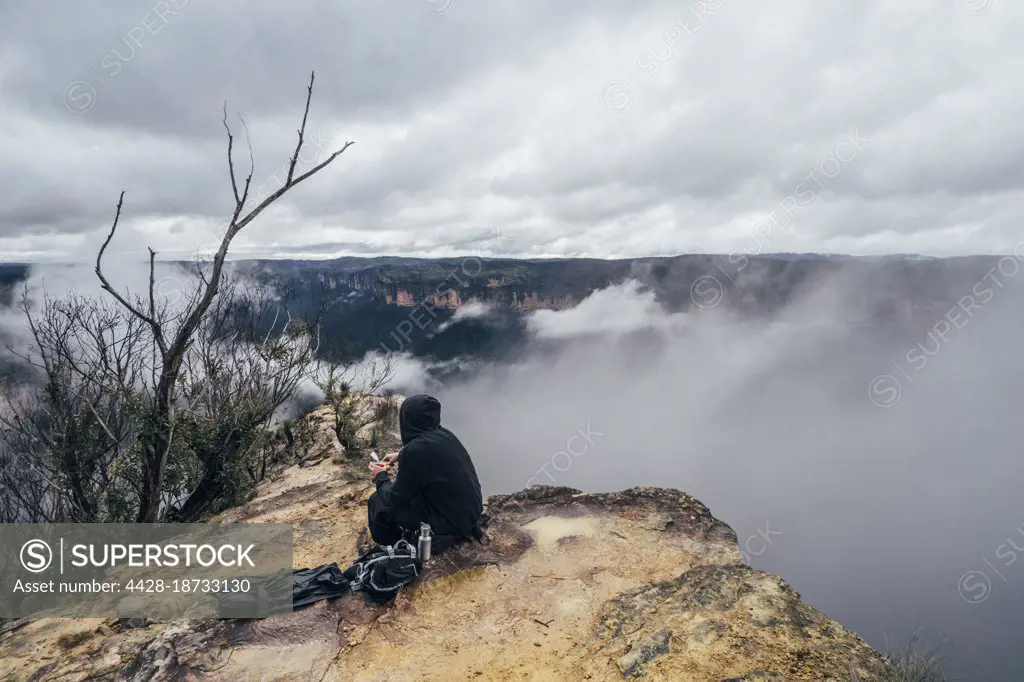 Male hiker resting on remote hilltop, Australia