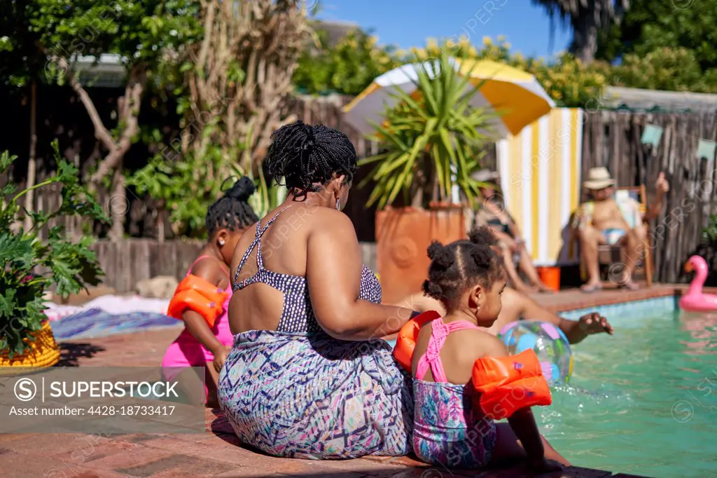 Mother and daughters at sunny summer swimming pool