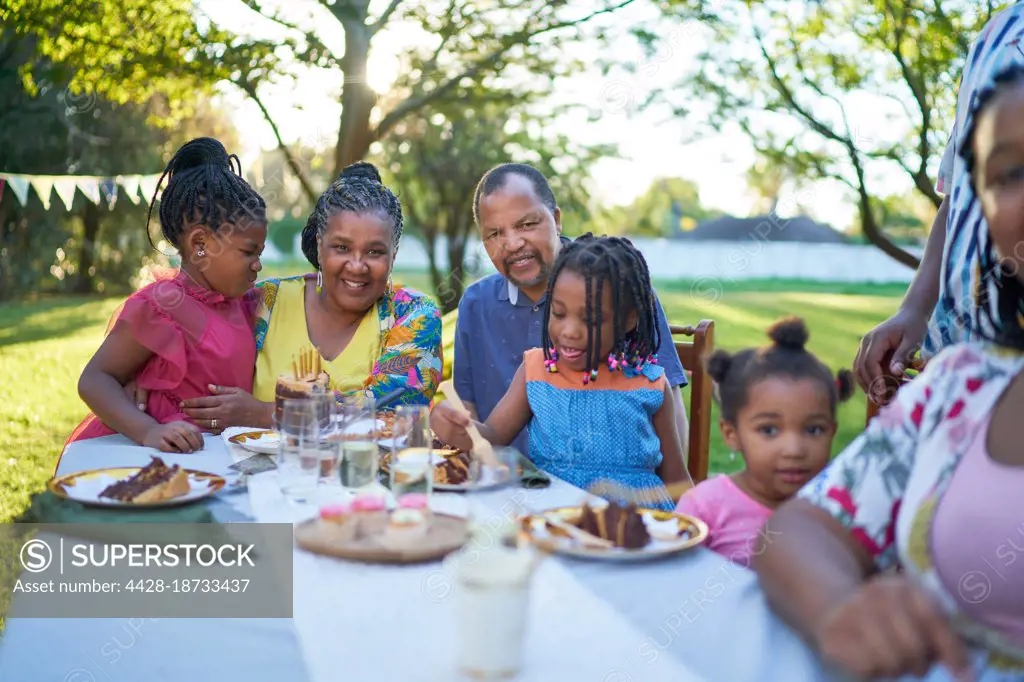 Happy multigenerational family celebrating birthday at patio table